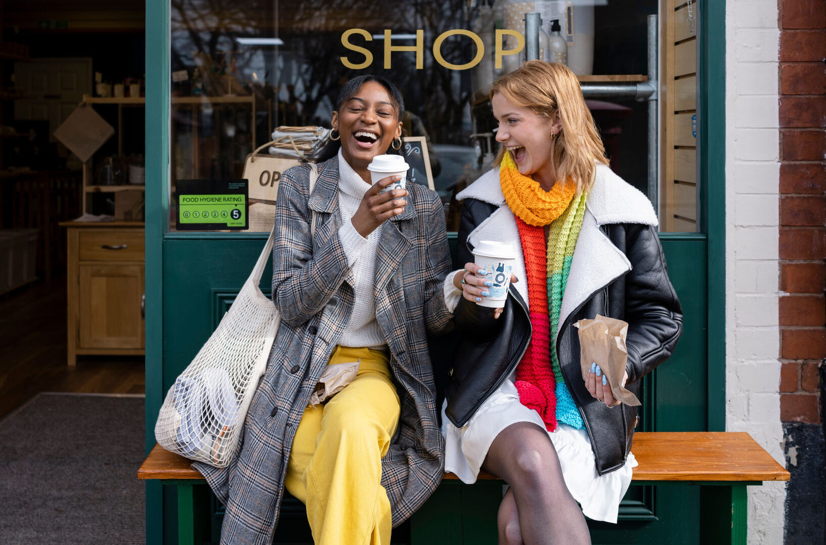 two friends sitting at cafe laughing